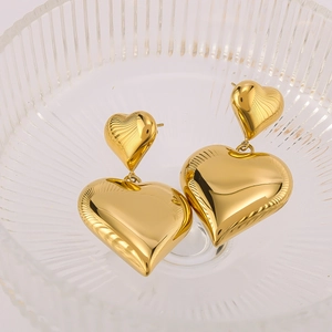 Double heart dangle earrings in 18K gold plated stainless steel on a glass bowl