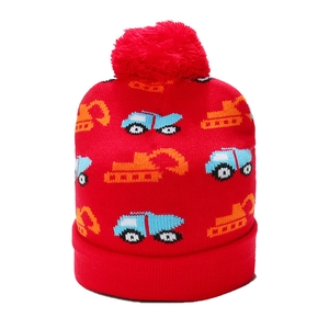 Close-up of red knit hat with colorful excavator embroidery and fluffy pompom detail