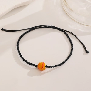 Detailed view of adjustable braided baseball bracelet with orange ball bead and red stitching