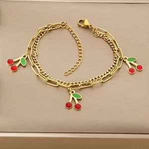 Detail of gold double-layered bracelet with red cherry pendants and lobster clasp