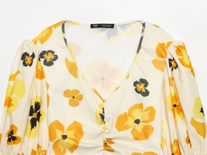 Detailed view of floral V-neck top showing ribbed texture and vibrant orange-yellow print