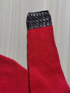 Dettaglio della maglia rossa e grigia mista su un maglione casual da uomo