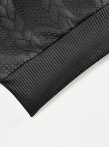 Close-up of black quilted diamond pattern and ribbed elastic knit hem on men's jacket