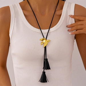 Golden bird pendant necklace with black tassels on adjustable cord shown on a model