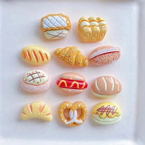 Flat lay of resin miniature bread and pastry charms on a tray for DIY crafts