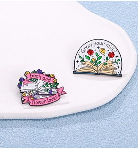 Macro detail of enamel flower and book pins with slogans Grow your mind and Book lover