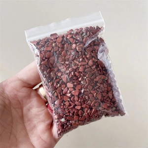 Close-up of small irregular red natural crystal stones in a transparent zip-lock bag