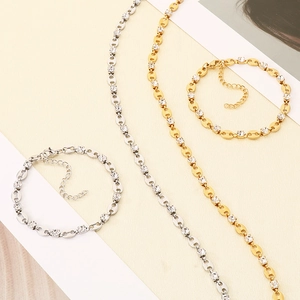 Flat lay of gold and silver coffee bean link necklaces and bracelets with inlaid zircons