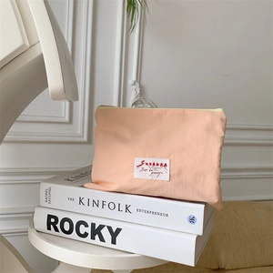 Detail of peach cream pouch with SOZAKKA logo on Kinfolk books in minimal setup