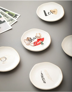 Detail of 4-inch irregular ceramic jewelry trays with gold rim and love motifs