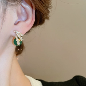 Primo piano dell'orecchino a perla verde smeraldo con metallo dorato e zircone