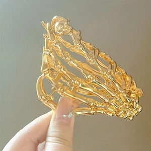 Detail of golden skeleton hand hair claw showing gothic bone structure and metallic finish