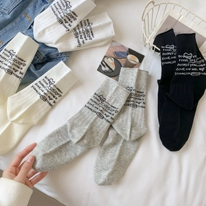 Three pairs of mid-calf cotton sports socks in white, grey, and black with letter patterns