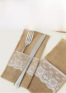 Detail of natural burlap cutlery holder featuring white crochet lace trim for holiday decor