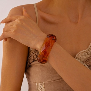 Detail of amber geometric resin cuff bracelet with polished faceted surface on model