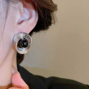 Makroaufnahme eines silbernen strukturierten Ohrrings mit schwarzer Perle am Model