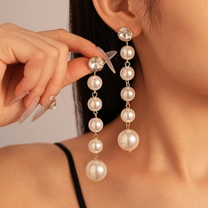 Vintage gold earrings with gradient pearls and rhinestones on elegant female model
