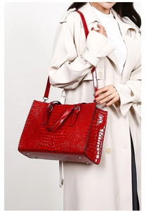 Detail of red crocodile embossed tote bag featuring glossy patent leather and silver hardware