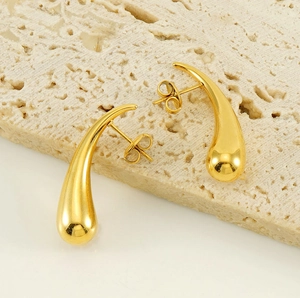 Detailed close-up of gold teardrop earrings with a polished mirror finish on stone