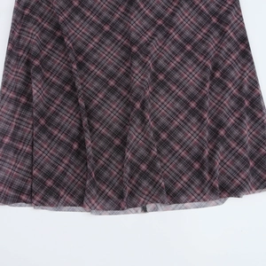 Détail de l'ourlet en maille à carreaux bordeaux avec couture fine sur une jupe sirène