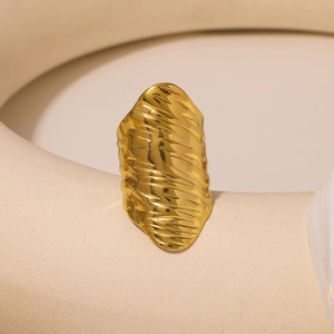 Exaggerated golden stainless steel ring with textured lava pattern in an artistic display