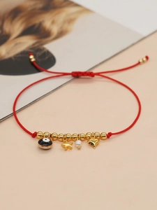 Detail of red braided evil eye bracelet with golden heart, star, and pearl charms