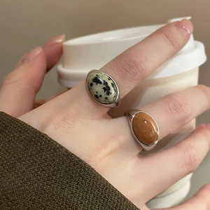 Close-up of silver minimalist rings with oval dalmatian stone and brown agate on hand