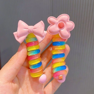 Detail of rainbow spiral hair ties with pink bow and flower accents for kids