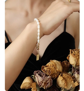 Detail of 18K gold-plated letter pendant on freshwater pearl bracelet worn by model