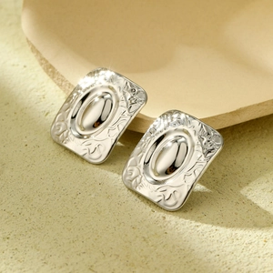 Detail of silver rectangular earrings with embossed texture and polished center oval