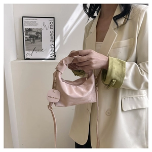 Detailed close-up of pink ruched crescent bag with knotted handle and fashion tag