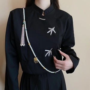 Detailed macro view of white pearl body chain with golden lotus charm and purple tassels