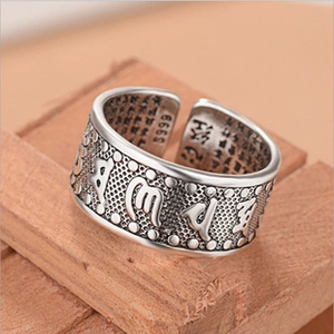 Macro detail of retro S999 silver wing ring with engraved Buddhist mantra symbols