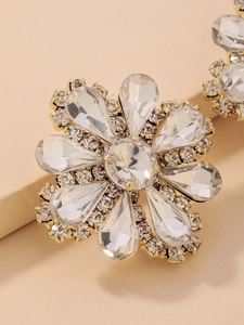 Macro shot of luxury gold flower stud earrings with sparkling clear crystal rhinestones