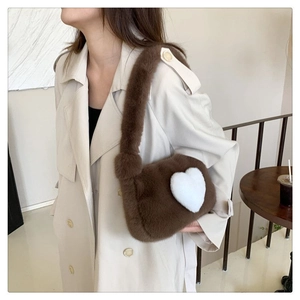 Detail of plush brown shoulder bag with a white heart pattern on soft faux fur fabric