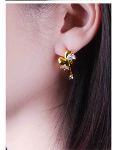 Detail shot of a 18K gold plated stainless steel heart earring with zircon stones on model
