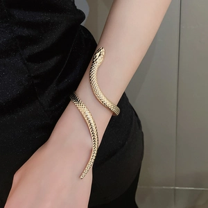Close-up of a gold snake-shaped cuff bracelet featuring detailed scale textures on the arm
