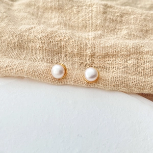 Detailed macro view of high-quality white freshwater pearl stud earrings with gold plating