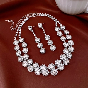 Detailed close-up of sparkling floral rhinestone necklace and earrings on red satin fabric