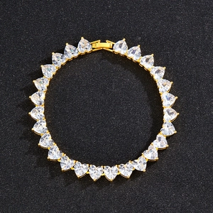 Close-up of golden tennis bracelet with heart-shaped cubic zirconia on black background
