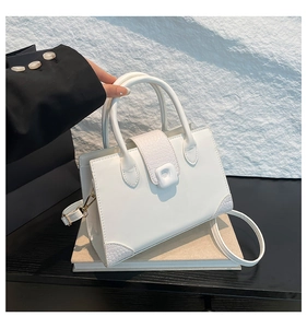 Close-up of white croc-embossed trim on a small square handbag with gold-tone hardware