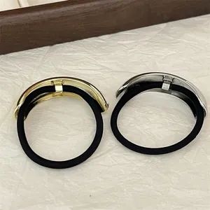Detail of minimalist gold and silver half-circle metal hair ties on white textured paper