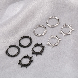 Macro shot of silver and black Mobius twist earrings with punk spikes on grey satin fabric