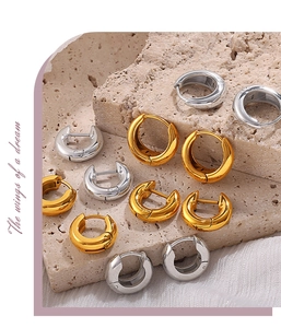 Artistic layout of chunky gold and silver hoop earrings on natural stone and white silk