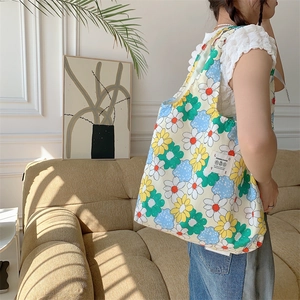 Dettaglio della borsa shopper in tela con motivi floreali colorati ed etichetta decorativa