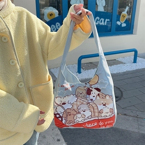 Detail of light blue canvas tote bag featuring cute cartoon dog prints and red bottom accent