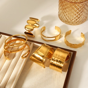 Collection of bold gold stainless steel open bangles with wave and textured designs