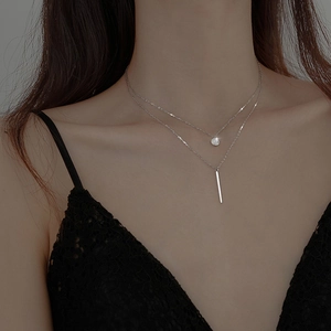 Detail of silver layered necklace featuring round zircon and vertical bar pendants