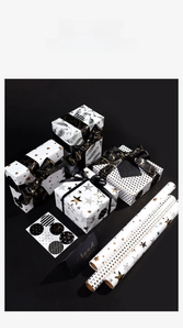 Detail of white gift wrap rolls with gold foil stars, feathers, and matching stickers