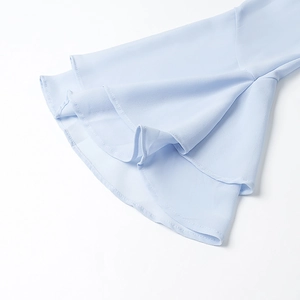Dettaglio delle balze in chiffon azzurro a strati con un drappeggio elegante